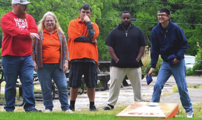 GRINNING, Garry Pennington starts a game of cornhole with help given, from left, by Jackson Breen, Suzan Breen, James Eubank and Jordan Griffin. TARA ALTIS | Staff