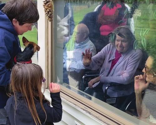 AT A WINDOW at the Valley Manor Nursing &amp; Rehabilitation Center, visitors and their dog offer comfort to facility residents during the Valley Manor pet parade.