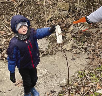 JASPER PROCTOR HELPS collect trash and hands it to Cody Proctor during the Earth Day cleanup. ELIZABETH BARNT | Staff