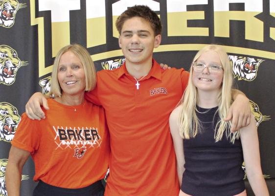FLANKED BY his mother Amber (left) and sister Everly, Booker O’Neill enjoys his signing ceremony to attend and play basketball at Baker University. MIRNDA JAMISON | Staff