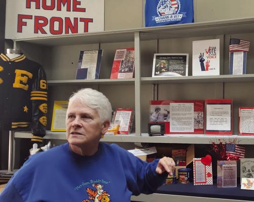 VOLUNTEER DEB FOSTER highlights the Home Front display in the “Not Forgotten” exhibit at the Excelsior Springs Museum, featuring birth announcements, community milestones and historical reporting from the Vietnam era. MIRANDA JAMISON | Staff