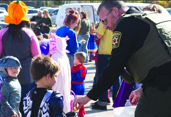 MAJ. ROBERT HAYES passes out candy at a trunk or treat event. Submitted