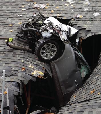A VEHICLE RESTS partially inside the roof of the Clay-Ray Veterans Hall after launching off the road and crashing into the same section damaged by a similar incident in February. SHARON DONAT | Staff