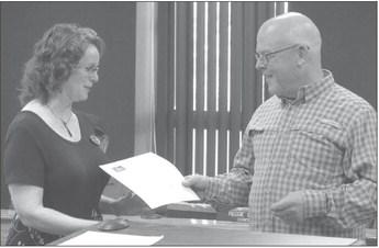 LAURA MIZE (FROM LEFT) and Mark Spohn shake hands after she recieved the “Good Neighbor Week” proclamation. ELIZABETH BARNT | Staff