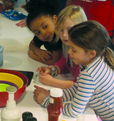 WHILE ATTENDING THE Kids in the Kitchen event, this young trio sizes up the implements and bowls lying wait for use along with the food. MIRANDA JAMISON | Staff