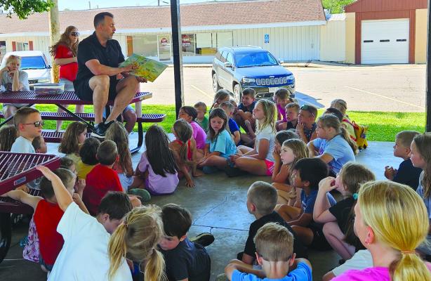 DR. NELSON KANNING of Kanning Dental reads a children’s book about good dental hygiene to youth participants during a program at Lawson City Park. After the story, kids colored dentalthemed activity pages. MIRANDA JAMISON | Staff