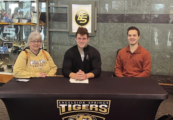 EXCELSIOR SPRINGS senior Lance Bown, flanked by his mother Jennifer and a friend, Justin Ford, signs his letter of intent to play football at Evangel University, an NAIA program based in Springfield. DUSTIN DANNER | Staff