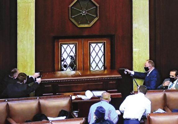 INSIDE THE U.S. HOUSE, law enforcers draw sidearms to prevent entry by insurrectionists.
