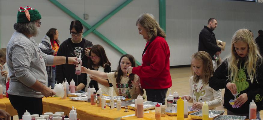 PARTICIPANTS POUR colored sand into small necklace jars.