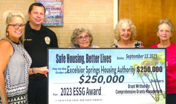 CARRIE HILTNER (from left), Police Captain Robert Warner, Barbra Blubaugh, Pat Owens and Sharon Williams holds up a check for $250,000 in grant funds for the Excelsior Springs Housing Authority. ELIZABETH BARNT | Staff