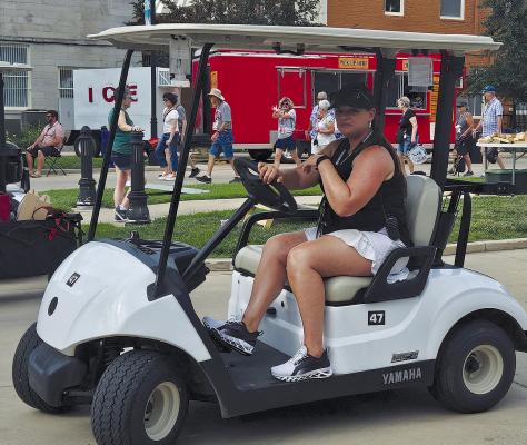 DOWNTOWN EXCELSIOR PARTNERSHIP Executive Director Lyndsey M. Baxter patrols the downtown streets in a golf cart to ensure that the event runs smoothly.