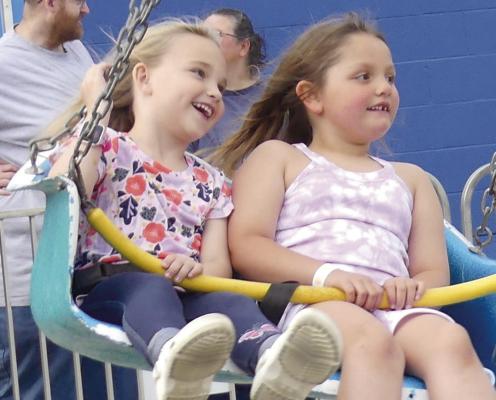 Maella Carter (left) and friend Camryn Lingle swung from above enjoying what the weekend carnival had to offer. ELIZABETH BARNT | Staff