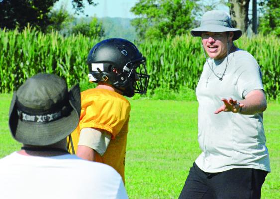 ASSISTANT COACH Chase Sims (right) explains defensive assignments and techniques during varsity 8-man football camp Monday at Orrick. SHAWN RONEY | Staff