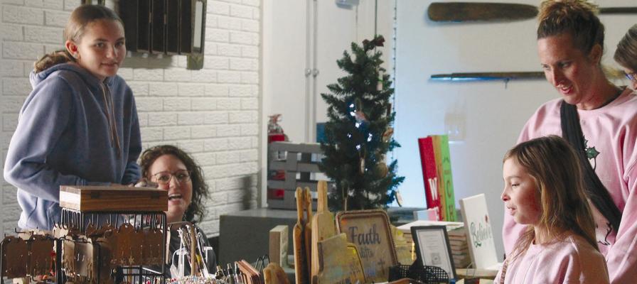 KAYLEE (LEFT) AND SHELENA (second from left) Guettermann assist shoppers from behind their booth during festivities at The Overlook at Crystal Lakes’ Hometown Holiday Bazaar. MIRANDA JAMISON | Staff