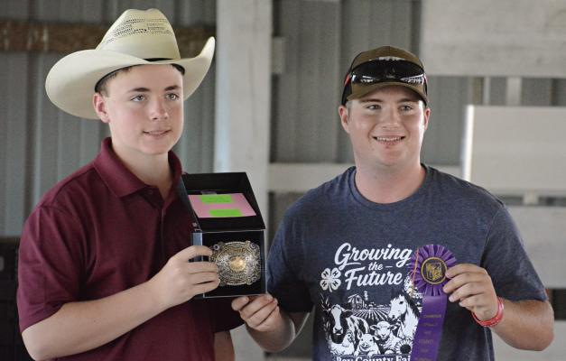 WESTON COVEY (left) helps display hardware won by Dantin McBee in shooting sports during this year’s Ray County Fair. McBee is an Excelsior Springs High School student and athlete, and a member of the Millville 4-H Club. SHAWN RONEY | Staff