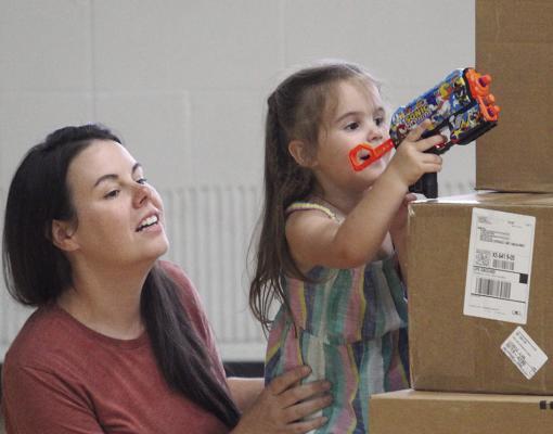 WITH THE HELP of her mother, Josie Harkins takes aim from behind a stack of boxes during the Nerf Wars event, hosted by Excelsior Springs Parks and Recreation and Community Center. MIRANDA JAMISON | Staff