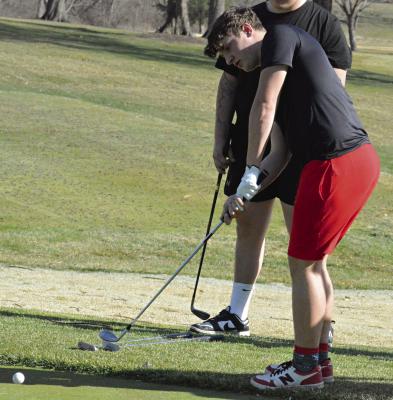 ATHLETES LIKE Orrick’s Jacob McElwee, shown attempting a chip shot at the Excelsior Springs Golf Course, are keeping March moving along at a supersonic pace with their many activities. SHAWN RONEY | Staff