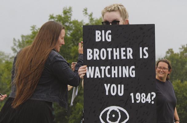 PROTESTERS GATHER ahead of the public forum on Flock cameras, with one displaying a sign referencing George Orwell’s novel “1984.” MIRANDA JAMISON | Staff