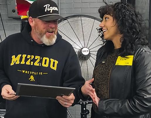 EXCELSIOR SPRINGS HIGH SCHOOL Football Coach and Teacher Jake Danneman (left) receives his Best Coach award from The Standard Lead Reporter Miranda Jamison during a surprise visit in front of his students during weightlifting class. SHARON DONAT | Staff
