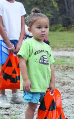 TAJ PHAN WAITS for her turn to collect candy from the next trick-or-treat trunk at the Fall Festival. .