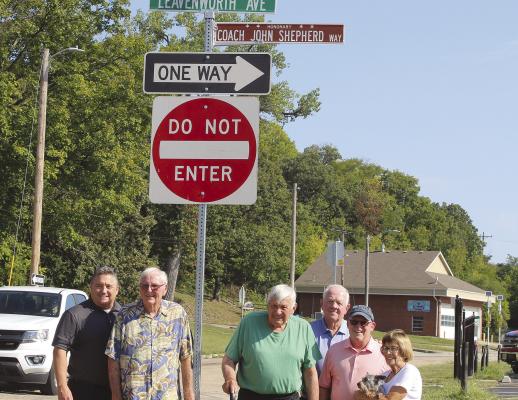 FRIENDS AND FAMILY stand with John Shepherd (center) in front of a sign dedicated to him near the new Lewis Elementary. Shephard dedicated his career to teaching for over 39 years in Excelsior Springs and also coached basketball and football. MIRANDA JAMISON | Staff