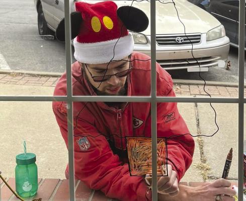 Robbie Farabee sketches Christmas art on the Richmond News window with window art markers. SOPHIA BALES | Staff