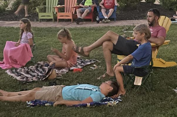 FROM LEFT, Josephine, Norah, Grant and Clifford with father Jason Van Till are among the 30 or more people enjoying the Movie in the Park event June 18, as Parks &amp; Rec plays “The Sandlot” on an inflatable screen in the Carolyn Schutte Pocket Park in downtown Excelsior Springs. EM RICE | Contributor