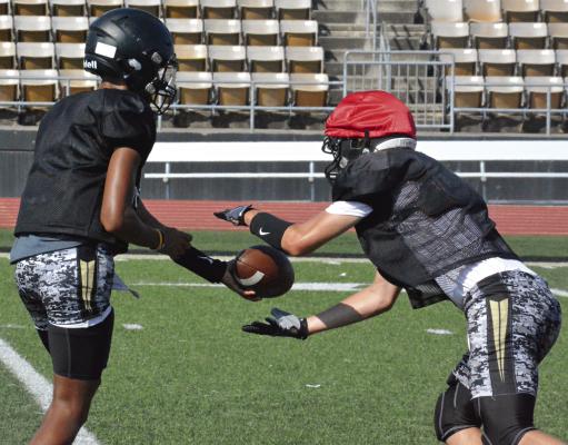 EXCELSIOR SPRINGS VARSITY QUARTERBACK Marquez McCant (left) hands off to Gaige Carr during Monday’s team camp session at Tiger Stadium, led by new coach Jake Danneman. SHAWN RONEY | Staff