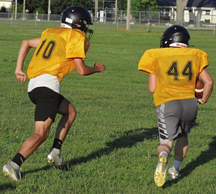 PARKER FLOYD (left) pursues running back Ozzden Ayers as Orrick runs through the circle drill during an offseason camp session. SHAWN RONEY | Staff