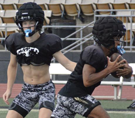 DALTON GUY (left) hands off to Nick Mubanga as the high school Tigers drill over their offense during an Excelsior Springs team camp session. SHAWN RONEY | Staff