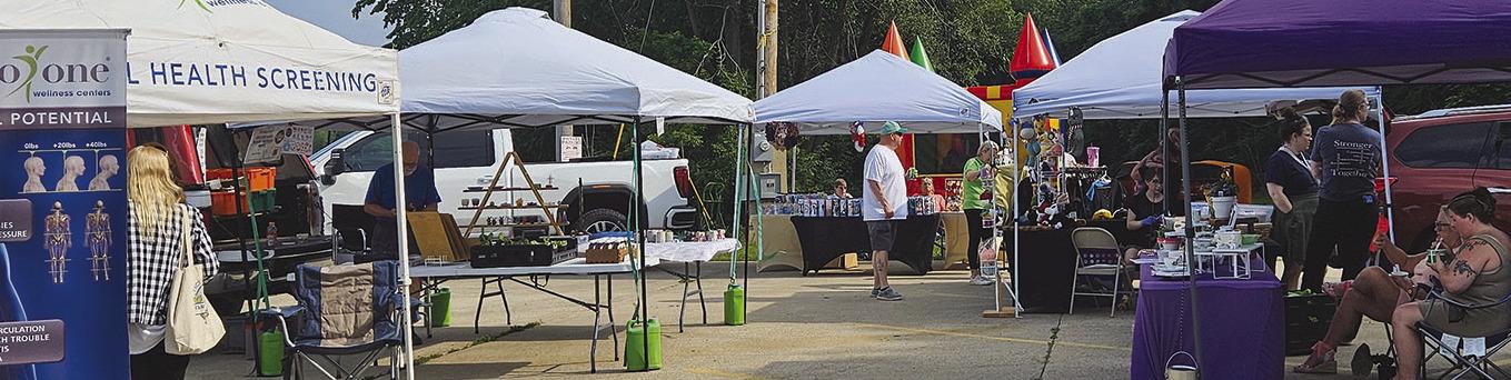 SHOPPERS BROWSE vendor booths during the farmers market’s opening night at the Clay-Ray Veterans Association lot. MIRANDA JAMISON | Staff