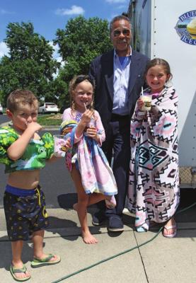 FREE ice cream for everyone at the Higginsville pool is gobbled by Dax Plymell, 4, and his sisters, Ellie Ryun, 6, and Marley Plymell, 6. Behind them, U.S. Rep. Emanuel Cleaver II pays for the ice cream while making sure parents know there is money in the mail coming for school-age children. J.C. VENTIMIGLIA | Staff