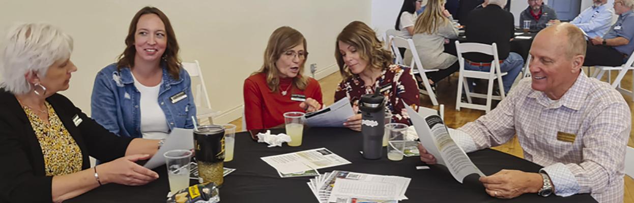 MICHELLE GOODE (from left), April Belcher, Kandi Harrison, Melissa Bartlett and Bill Hightower look over a community survey at the Excelsior Springs Chamber meeting. MIRANDA JAMISON | Staff