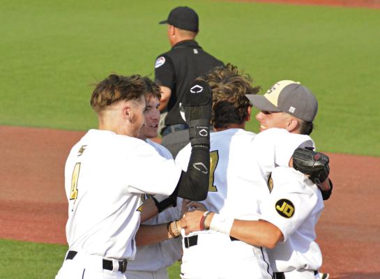 KAELAN BEDFORD, his jersey number (7) partially obscured, gets mobbed by his teammates after hitting the game-winning single. Those swarming around him include Brendan Blackburn (No. 4).