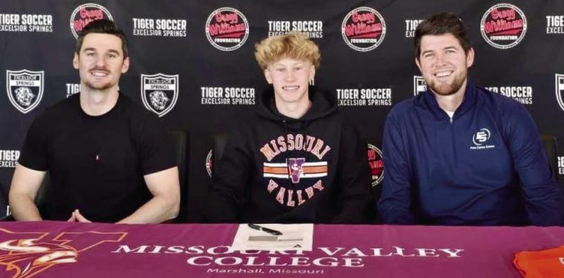 KOLIN KINCAID (center) is joined by Excelsior Springs varsity assistant coach Brett McKenzie (left) and head coach Zac Ganzer as he signs his letter of intent to attend and play for Missouri Valley College, a private, NAIA-affiliated school in Marshall. DUSTIN DANNER | Staff