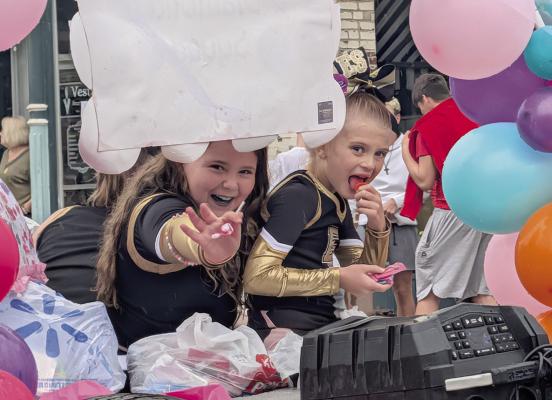 SCARLETT MCKINNEY (left) greets parade-goers from aboard the youth cheerleading float. MIRANDA JAMISON | Staff
