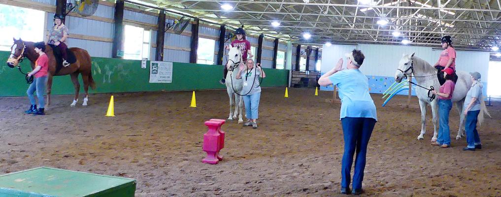 STUDENTS LISTEN to their instructor after a morning of riding lessons. ELIZABETH BARNT | Staff