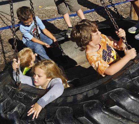 LEWIS ELEMENTARY students play on a tire swing before taking a lunch break at Fun Farm.