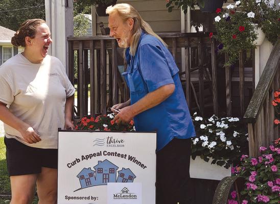 ROBERT ST. JOHN (right), Thrive Excelsior’s August Curb Appeal Contest winner, receives an Ace Hardware gift card from McLendon Seamless Guttering co-owner Whitney Sparks. St. John’s colorful display of impatiens and other flowers, which regularly attracts hummingbirds, helped his Park Avenue property earn the monthly honor. MIRANDA JAMISON | Staff