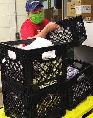 FOOD DISTRIBUTION includes milk, which Stacey Robeson loads onto a cart to push toward waiting school buses.