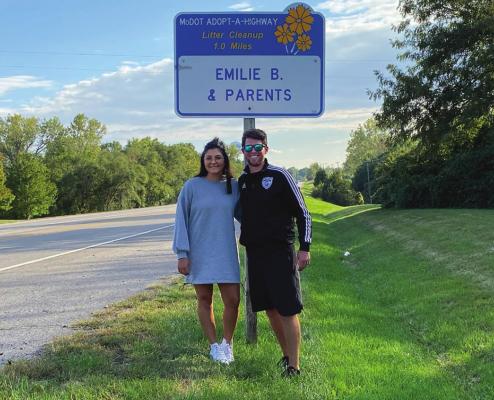 UNDER the Adopt-A-Highway sign are Emilie Barrera and Zac Ganzer. SAMANTHA ZELAYA | Staff affilate