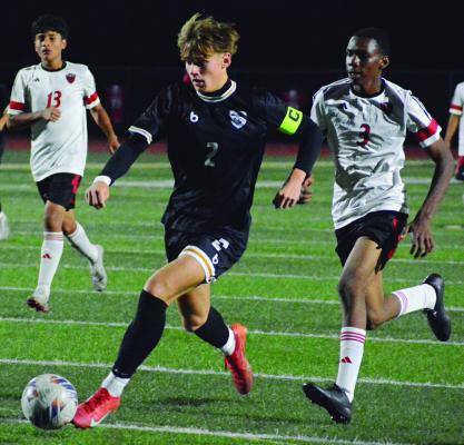 BRADY SCHOONOVER (left) dribbles toward the goal as a college of Cardinals pursue him during Excelsior Springs’ rout of Raytown South. SHAWN RONEY | Staff