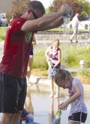 Drake Pollard gets his daughter Emery Pollard wet with a sponge while playing in the water. ELIZABETH BARNT | Staff