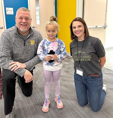 Kindergartener Khai Winn holding her free pair of Bombas socks poses for a photo with Brian Sloan, principal of Cornerstone Elementary and Sarah Baker, executive director of the Excelsior Springs Educational Foundation.