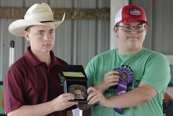 WESTON COVEY (left) helps display hardware won by Hunter Crowley in shooting sports during this year’s Ray County Fair in Richmond. SHAWN RONEY | Staff