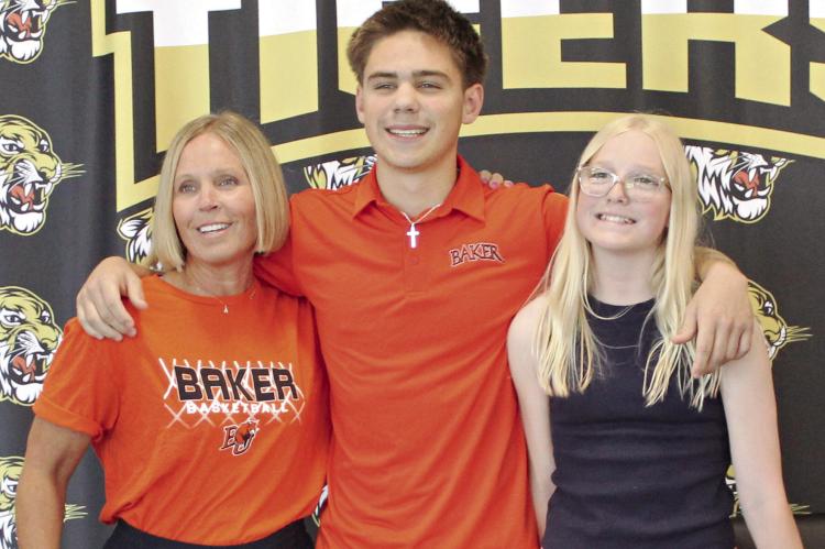 FLANKED BY his mother Amber (left) and sister Everly, Booker O’Neill enjoys his signing ceremony to attend and play basketball at Baker University. MIRNDA JAMISON | Staff