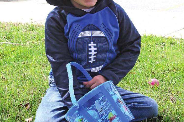 WITH A SMILE, Aden Pettiecord, 3, shows his pleasure when putting his first Easter egg into his hunting basket.