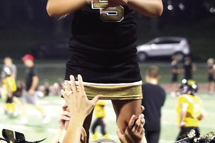 SOPHIA WALSTON reaches the top of a stunt as fellow cheerleaders support her from below.