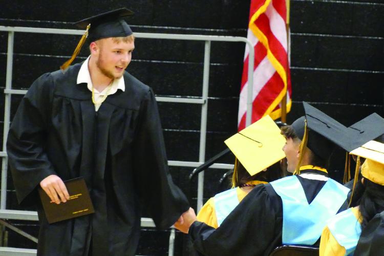 CARSON ASHLEY shakes hands with fellow classmates after receiving his diploma.