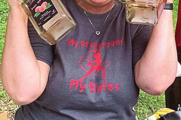 RONDA BOYER happily models one of Top Hat Winery’s products: Just Peachy Whiskey. In addition to wines, guests are treated throughout the festival to a variety of whiskeys and craft beers.